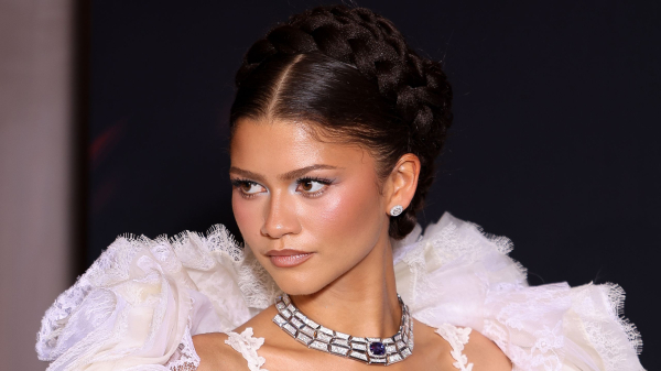 Zendaya wears a white dress and braid crown with blue eye shadow.